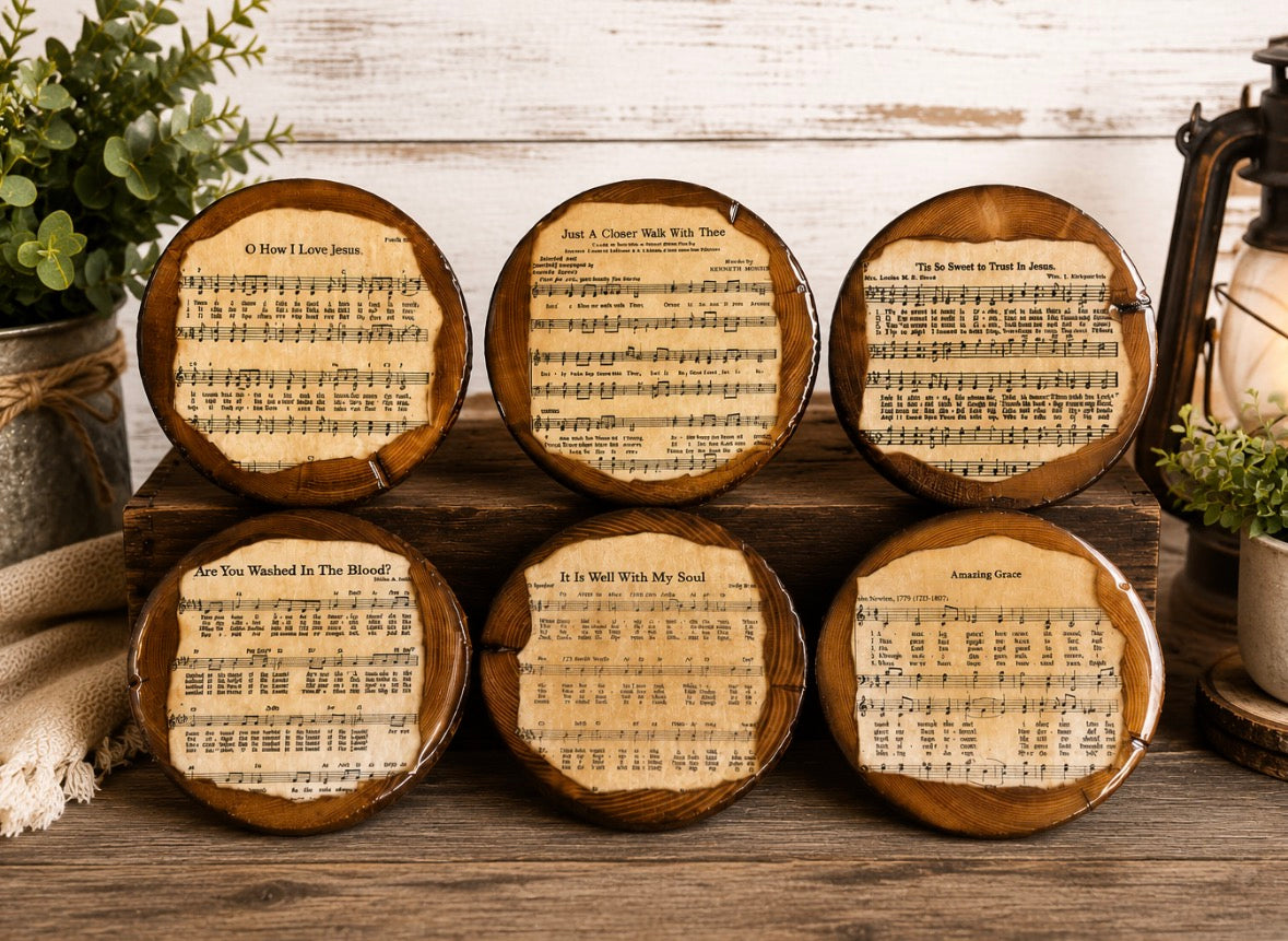 Six round coasters featuring vintage sheet music designs with song titles and musical notes, arranged on a rustic wooden surface with decorative plants and a lantern in the background.